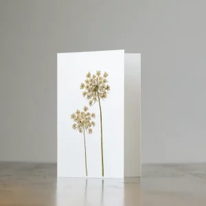 Tarjeta abierta con flores prensadas sobre superficie de madera