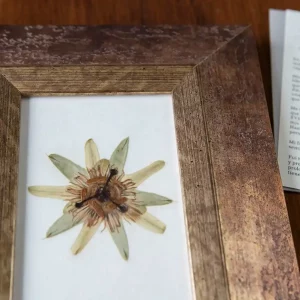 Detalle del marco artesanal con acabado cobrizo en ángulo y textura de pan de oro.